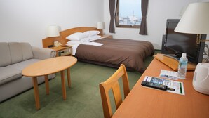 A hotel room with a bed, a sofa, a table, a TV, and a window with a city view. - FREX HOTEL (Matsusaka)