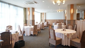 A hotel dining area with round tables, chairs, and a patterned carpet. - FREX HOTEL (Matsusaka)