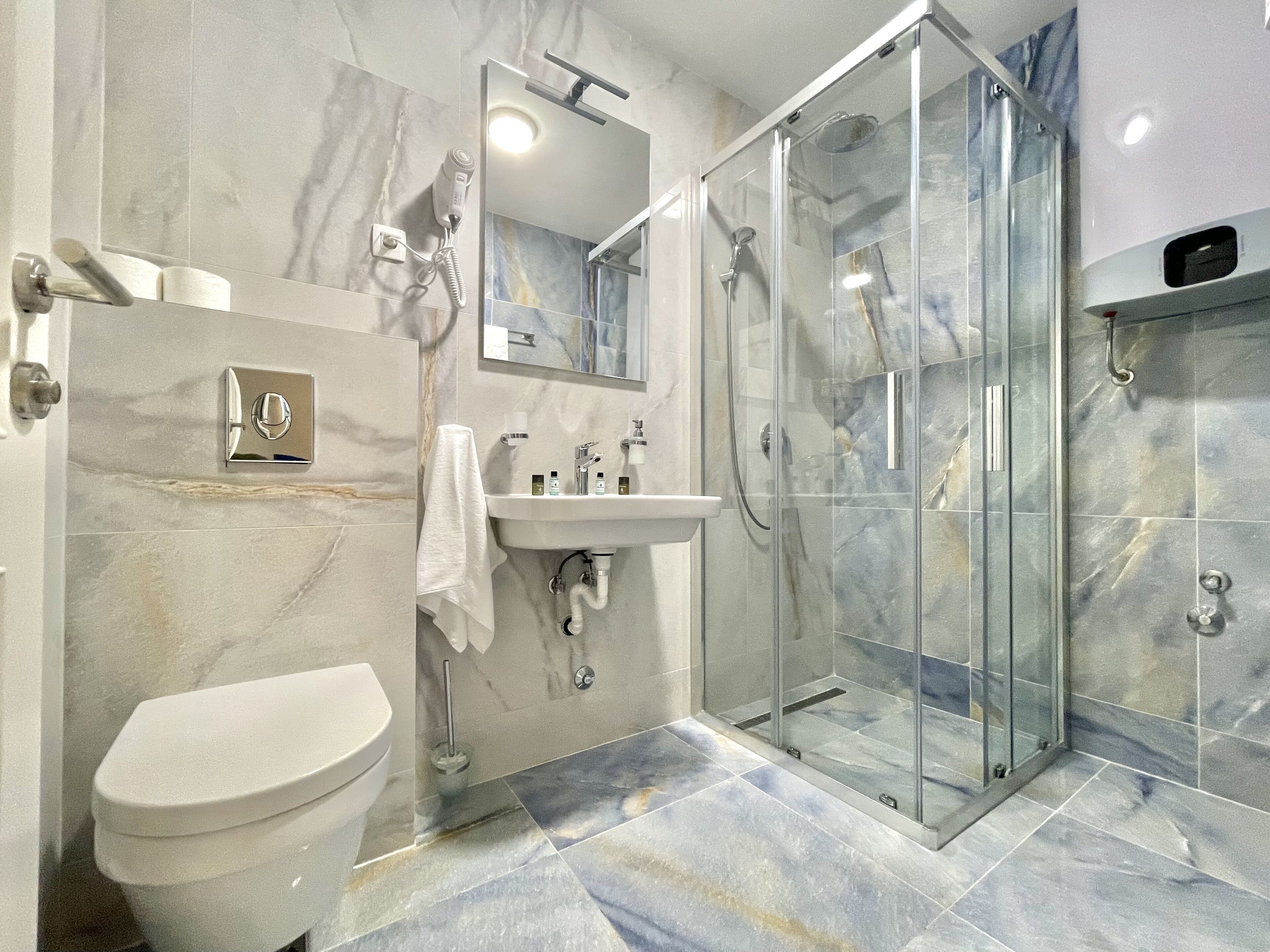 Un baño moderno con inodoro, lavamanos y ducha envuelta en vidrio.
