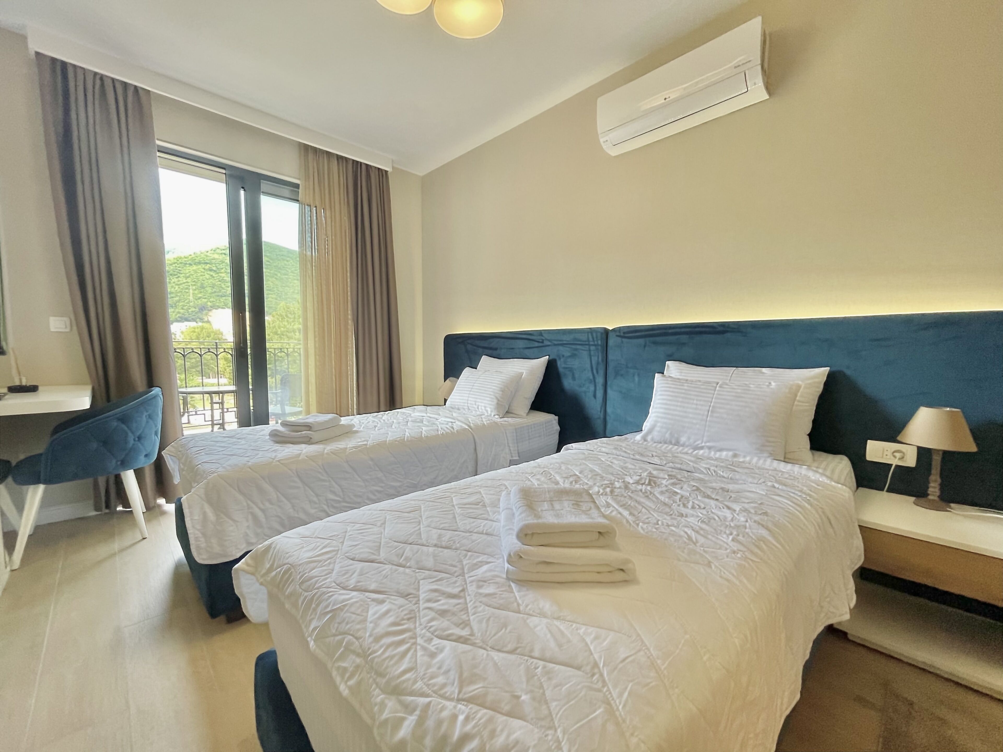 A hotel room with two beds, a desk, and a chair.