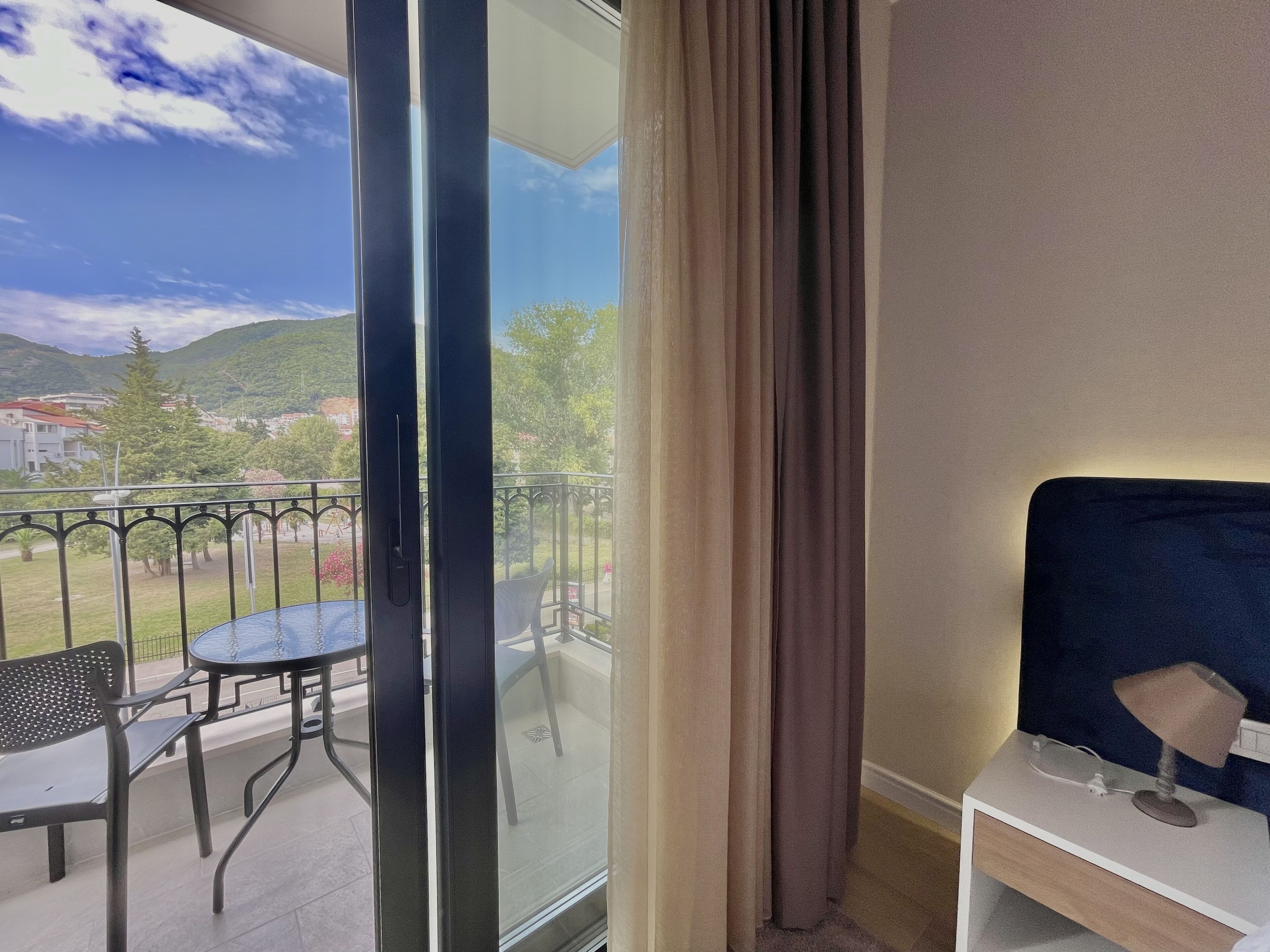 Ein Balkon mit Tisch und Stühlen, Blick auf die Landschaft und ein Nachttisch mit Lampe.