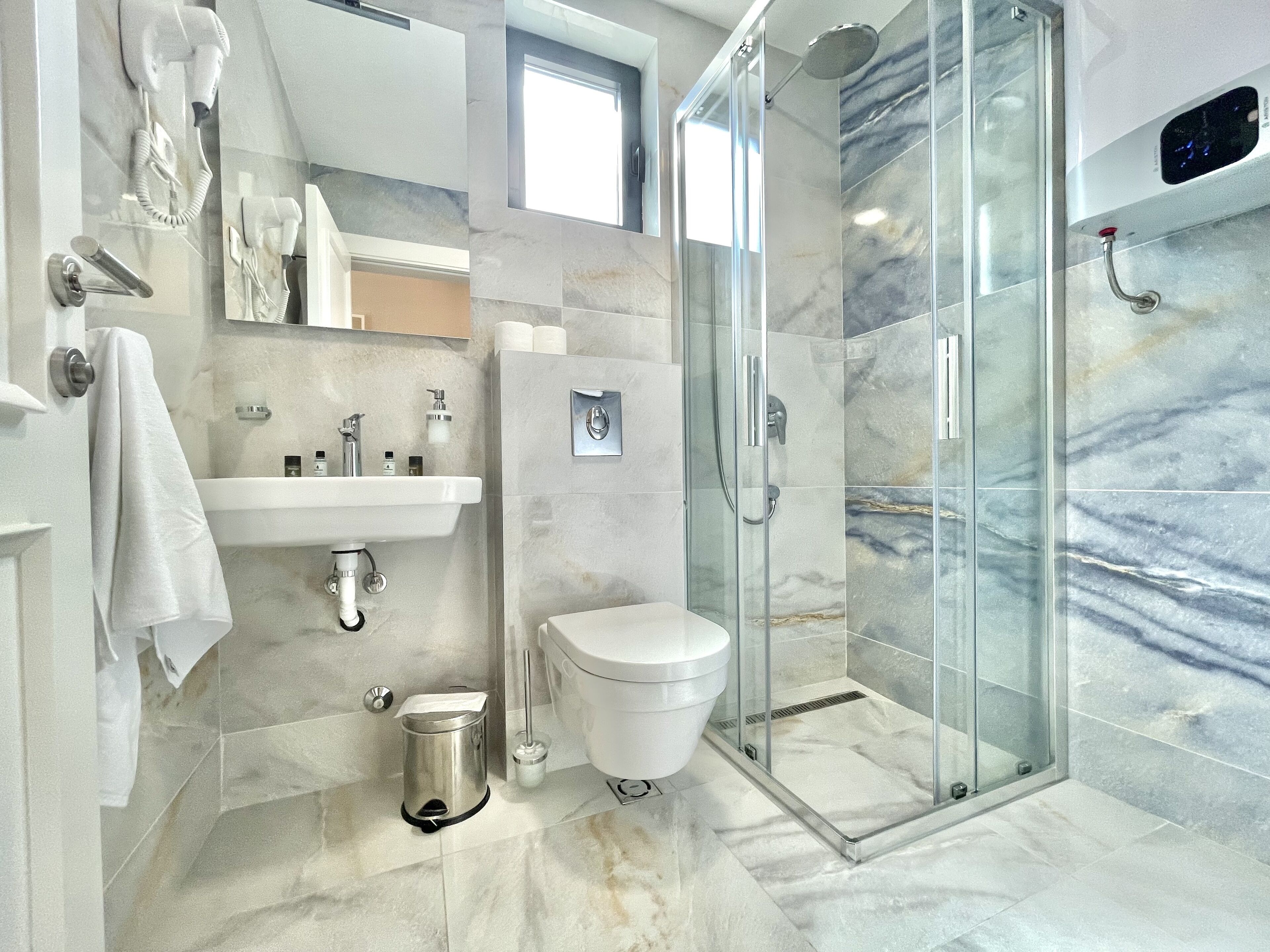 A modern bathroom with a glass-enclosed shower, a white sink, and a toilet.