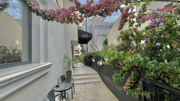 An outdoor seating area with a table and chairs, a staircase, and a wall covered with flowering vines. - Comfort Apartments Pasha  (Budva)