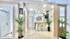 A modern hotel lobby with a reception desk, two yellow chairs, and potted plants. - Comfort Apartments Pasha  (Budva)