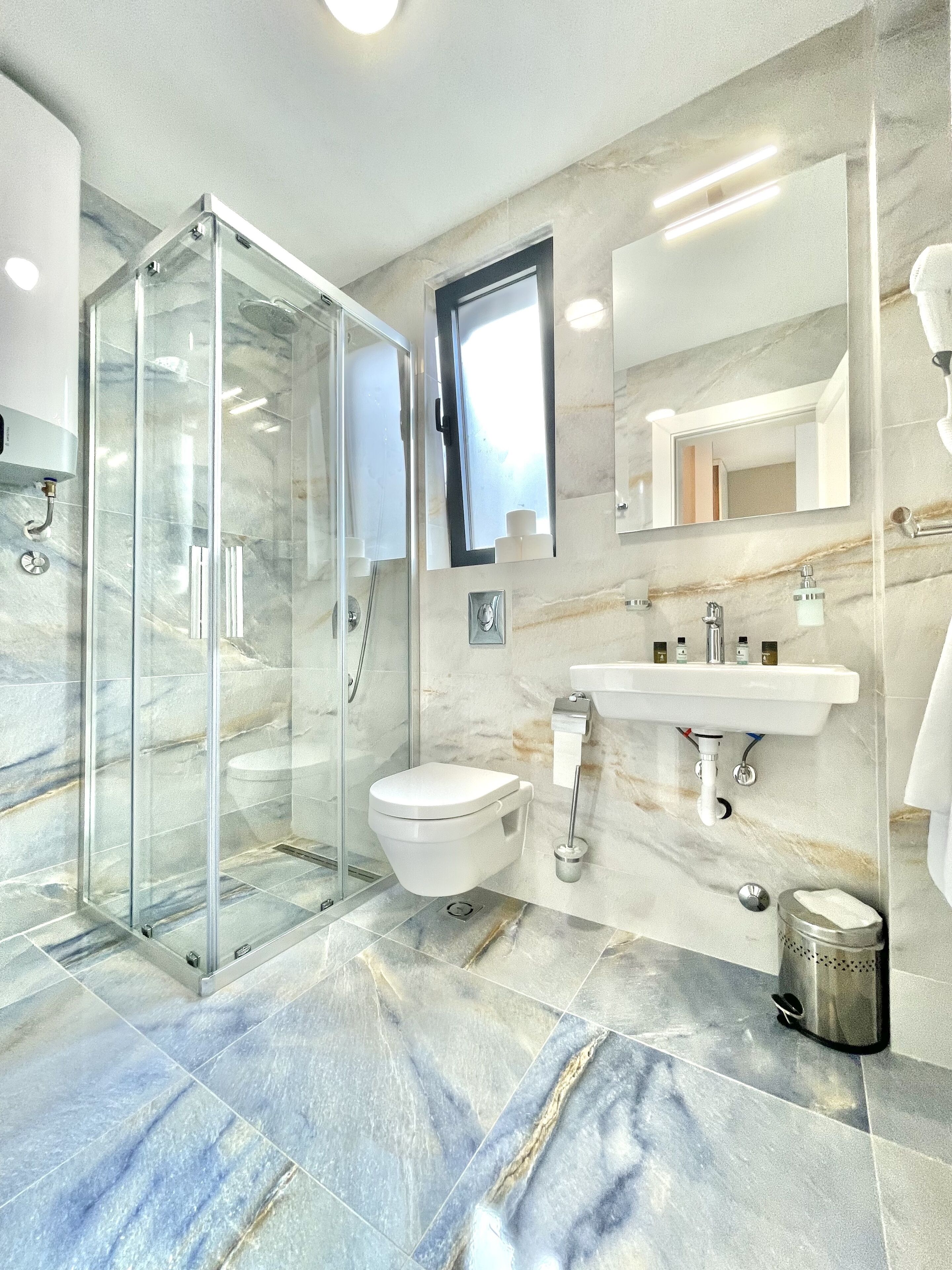 A modern bathroom with a glass-enclosed shower, a toilet, a sink, and a mirror.