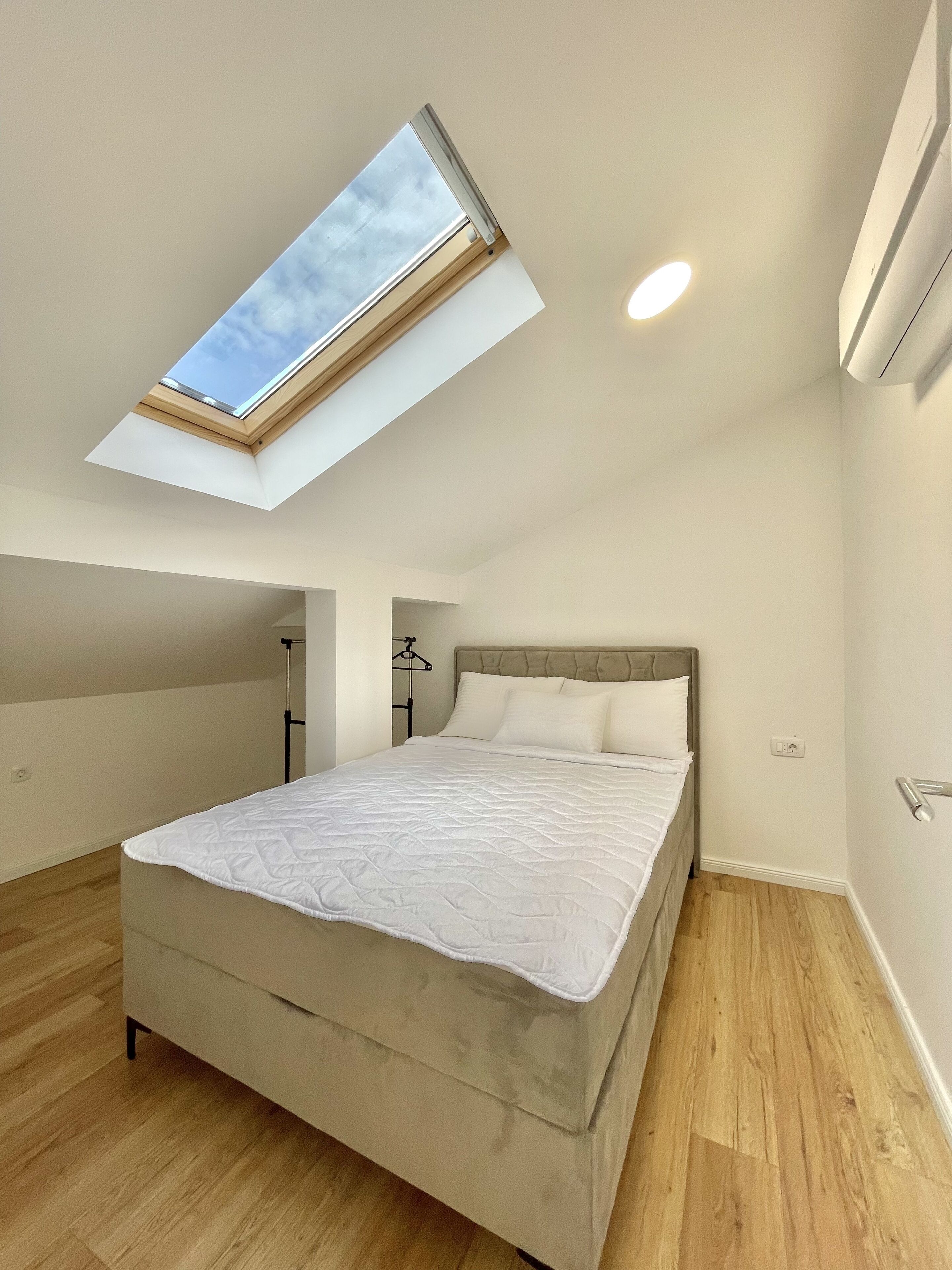 Una camera da letto con una finestra sul tetto, un letto e un armadio.