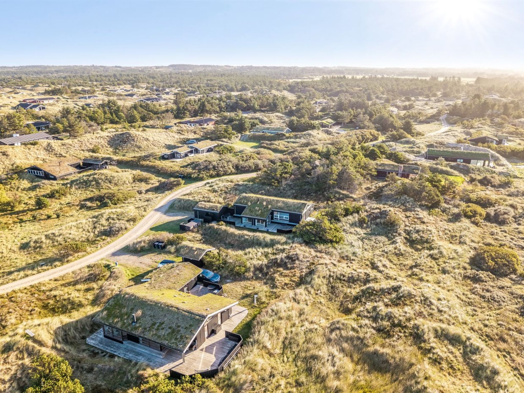 Bairro residencial com várias casas, incluindo uma com destaque, que possui um amplo deck e um design de telhado único.