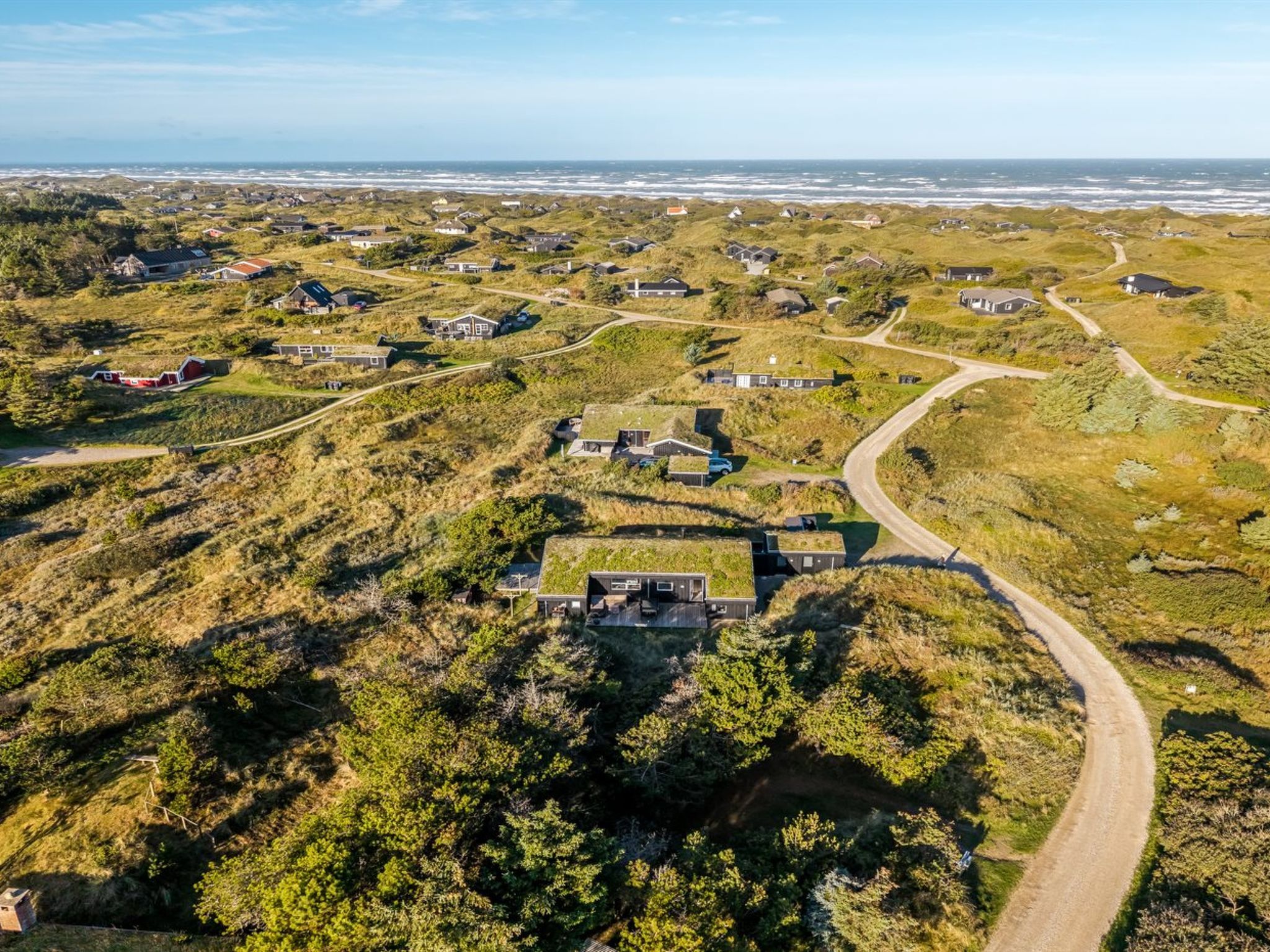 An aerial view of a coastal settlement with houses, roads, and a beach.