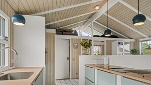 A modern kitchen with a wooden ceiling, a tiled floor, and pendant lights.