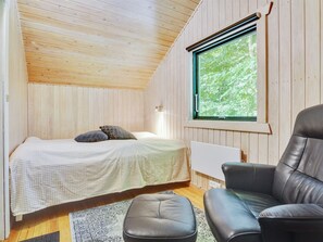A small, cozy room with a bed, a chair, and a window.