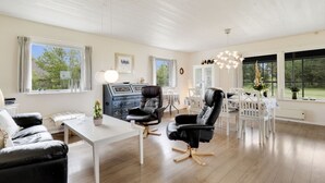 A spacious room with a white ceiling, large windows, a black leather chair, a white table, and a white cabinet. - "Mikkeline" - 400m to the fjord by Interhome (Øster Assels)