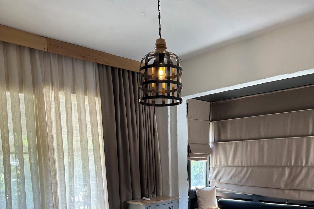 A hotel room with a bed, a bedside table, a lamp, and a window with curtains.