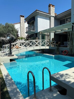 A swimming pool with a white fence, a stone chimney, and a balcony with outdoor furniture. - Argente Alacatı Adult Only (Cesme)
