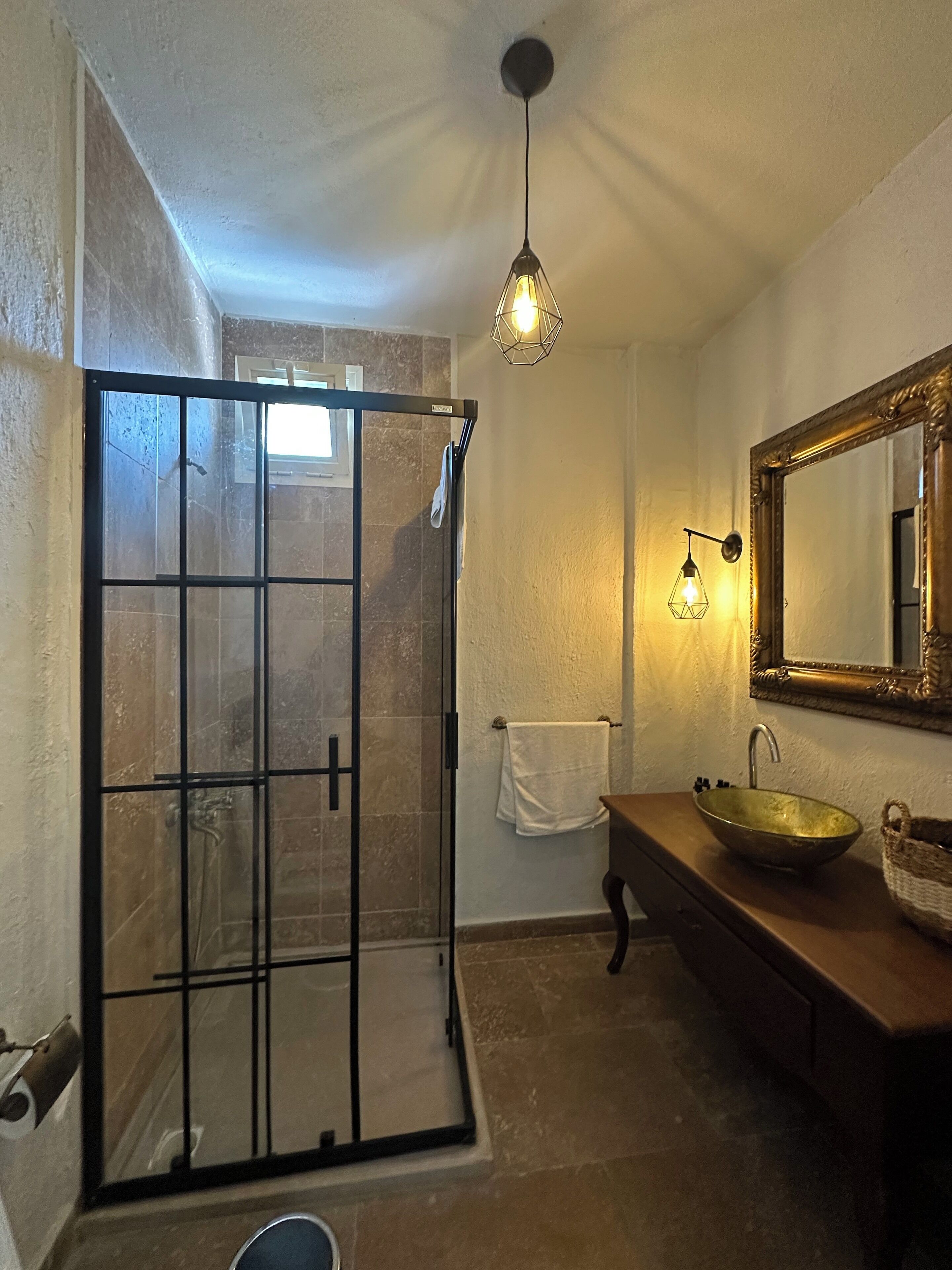 Un baño con cabina de ducha de vidrio, tocador de madera con lavamanos integrado y un espejo grande.