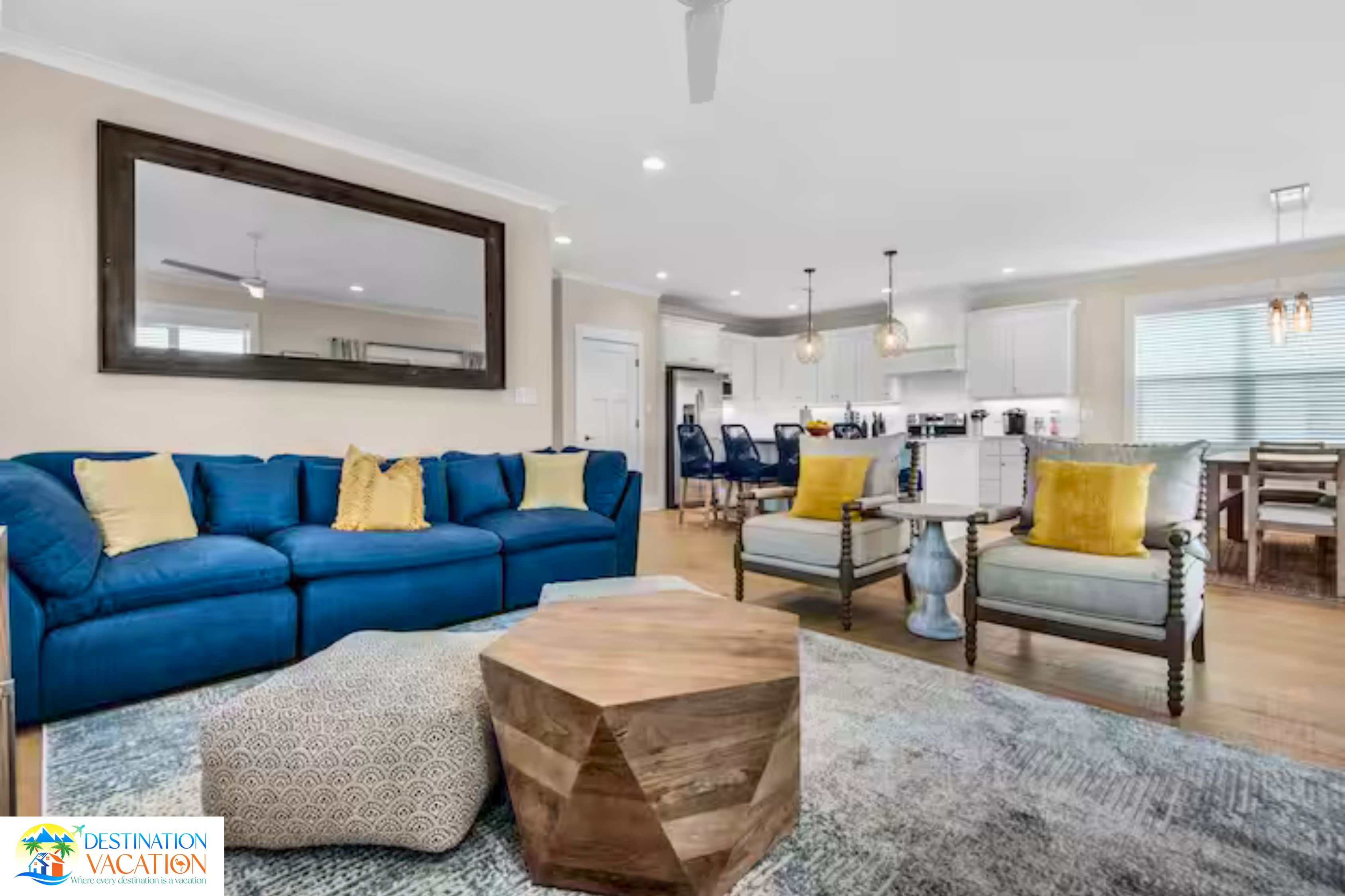 Un salon moderne avec un canapé bleu, une table basse en bois et un coin repas agrémenté d’un lustre.