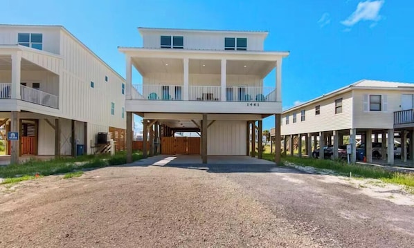 A two-story building with a covered entrance and a gravel driveway. - Gulf Shores Getaway: Private Pool + Pickleball Court (Gulf Shores)