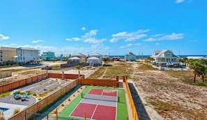 A beachfront property with multiple buildings, a tennis court, and a sandy beach area. - Gulf Shores Getaway: Private Pool + Pickleball Court (Gulf Shores)