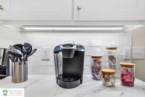 A kitchen with a coffee maker, utensils, and jars of sugar and spices. - Gulf Shores Getaway: Private Pool + Pickleball Court (Gulf Shores)