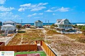 Una propiedad frente a la playa con varias casas, un sendero de arena y una valla de madera.