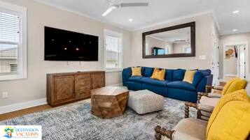 Un salon avec un canapé bleu, un meuble en bois et un ventilateur de plafond.