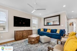Un salon avec un canapé bleu, un meuble en bois et un ventilateur de plafond.