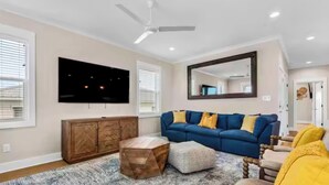 Ein Wohnzimmer mit einem blauen Sofa, einem Holzkasten und einem Fernseher an der Wand.