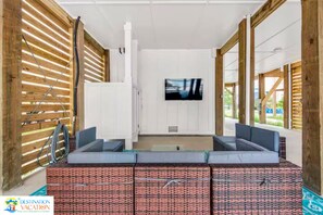 A modern interior with a flat-screen TV mounted on a white wall, a sectional sofa, and a wooden slatted wall on the left.