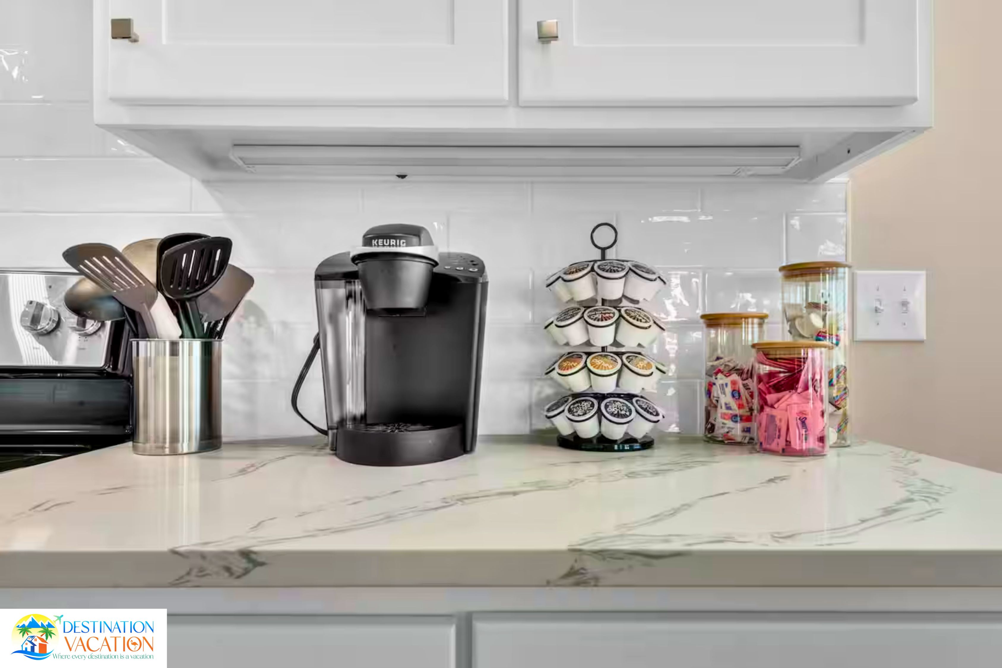 Un plan de travail de cuisine avec une machine à café, un ensemble d’ustensiles, un objet décoratif et un bocal de collations.