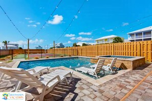 A swimming pool with lounge chairs and a wooden fence. - Beachside Escape w/ Pool, Views & Pickleball Fun (Gulf Shores)