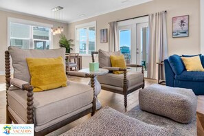 Un salon comprenant deux fauteuils, un canapé, une table basse et un pouf à motifs.