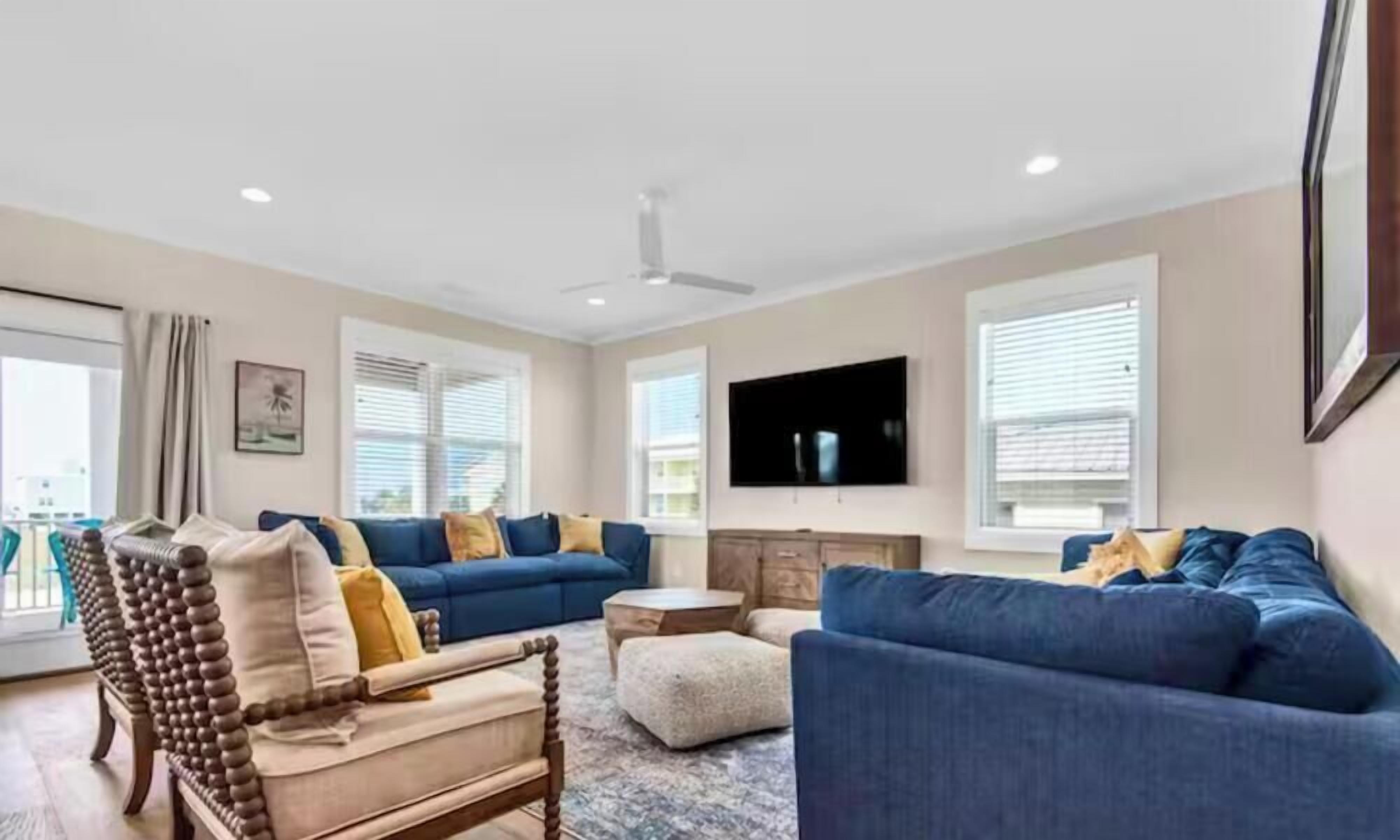 A living room with a sofa set, a television, and a ceiling fan.