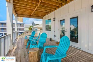 Une terrasse extérieure couverte, dotée d’un plancher en bois et de chaises bleues.