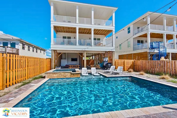A two-story building with a swimming pool, wooden deck, and a covered patio area.