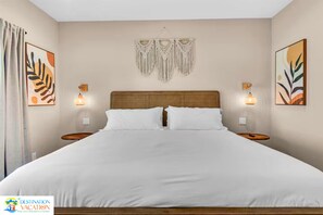 A hotel room with a large bed, two bedside tables, a wooden headboard, and wall-mounted artwork.