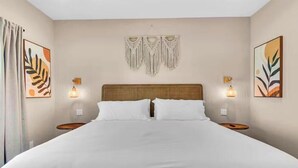 Ein Hotelzimmer mit einem großen Bett, zwei Nachttischen, Wandlampen und gerahmten Kunstwerken an den Wänden.