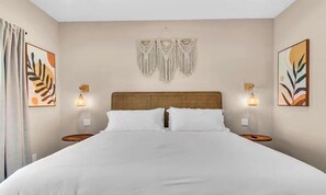 Una camera d'albergo con un letto grande, due comodini, lampade a parete e opere d'arte incorniciate alle pareti.