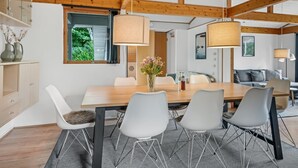 Ein moderner Essbereich mit einem Holztisch, weißen Stühlen und Pendelleuchten.