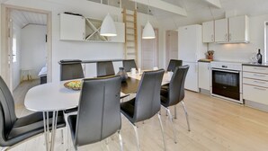 Een moderne keuken met een eethoek, uitgevoerd in wit en zwart, met houten vloeren en een loft-stijl plafond.