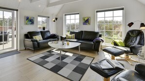 Een ruime woonkamer met een hoge plafond, grote ramen en moderne meubels.