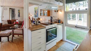 Une cuisine compacte avec des meubles blancs, un four encastré et un coin repas comprenant une table et des chaises en bois.