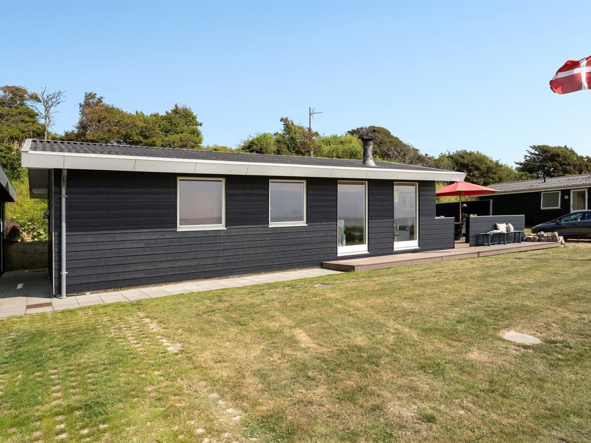 A modern single-story house with a dark exterior, large windows, and a small deck area.