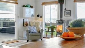 A cozy living room with a fireplace, a comfortable armchair, and a view of the outdoors. - "Akseline" - 20m from the sea by Interhome (Assens)