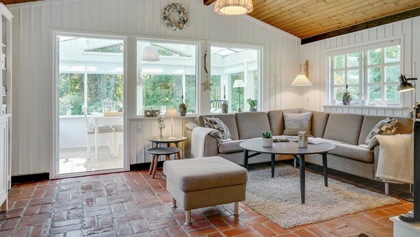 Een gezellige woonkamer met een houten plafond, een bank, een bijzettafeltje en een open haard.