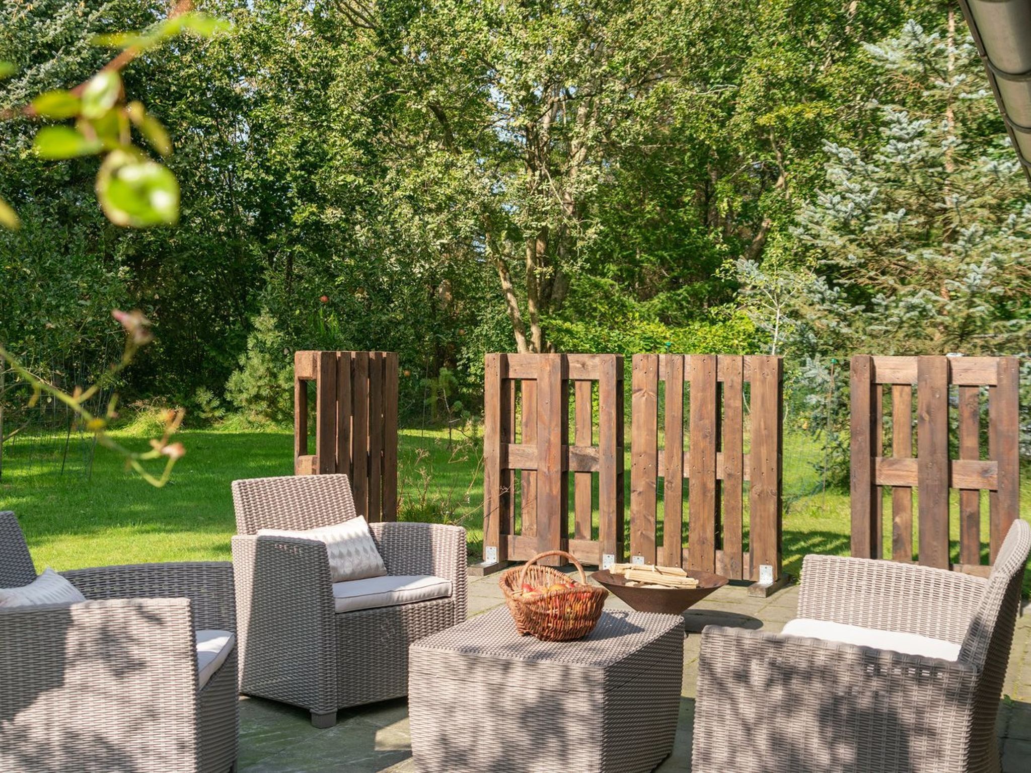 Un patio al aire libre con mobiliario de mimbre y una chimenea.