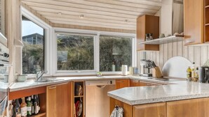 Cocina moderna con armarios de madera, encimera de granito y un amplio ventanal con vistas al exterior.