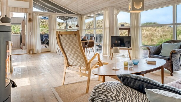 Un amplio espacio de sala con un gran ventanal, techo de madera y una acogedora disposición de asientos.