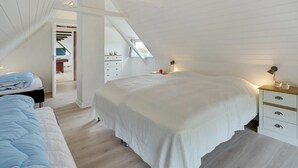 Une chambre spacieuse située dans les combles, avec un grand lit, un bureau et une commode.