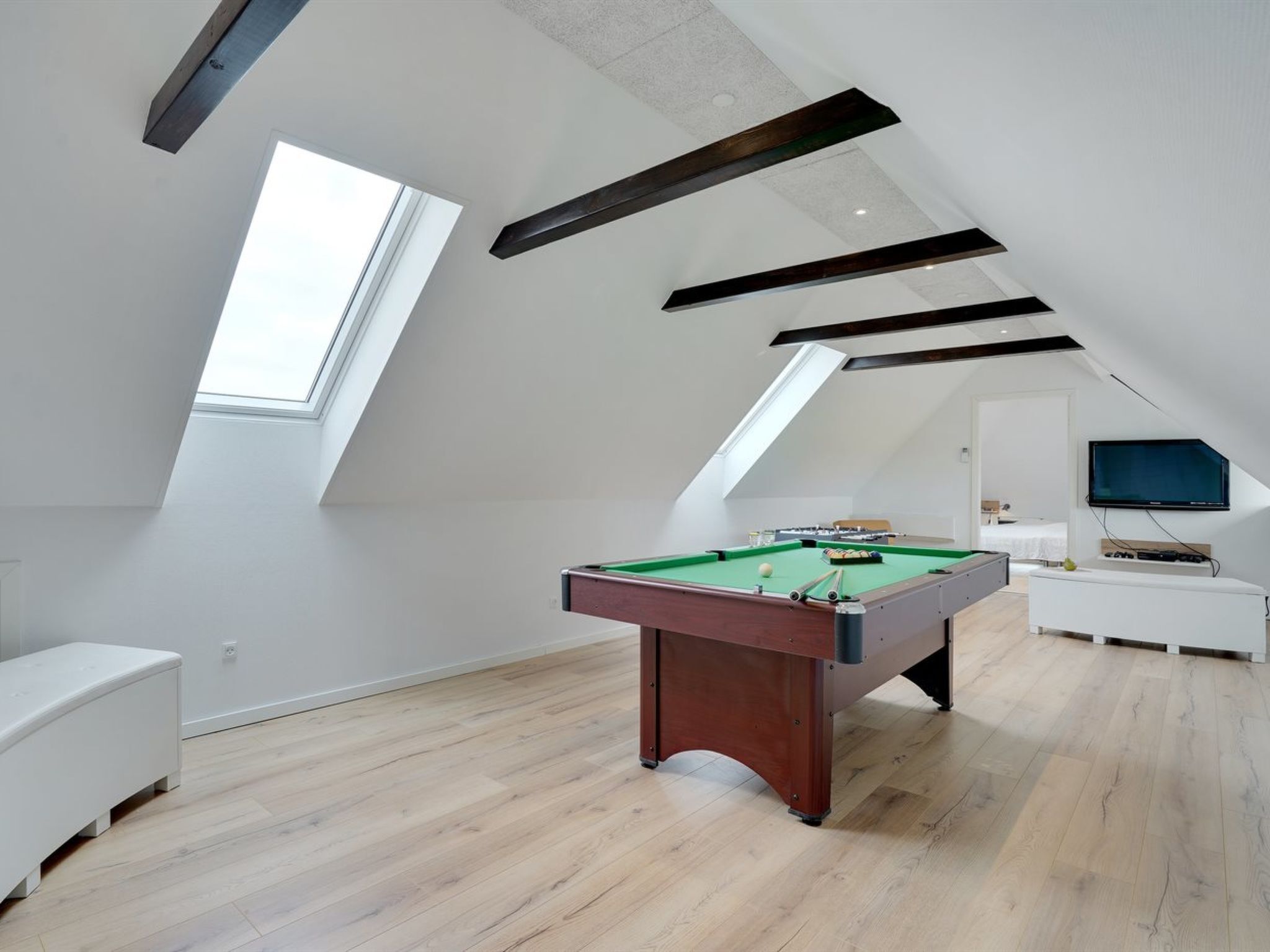 Une pièce moderne équipée d’une table de billard, d’un téléviseur fixé au mur et d’une lucarne.