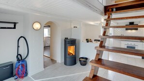 Une cuisine moderne avec des meubles blancs, une cuisinière noire et un escalier en bois.