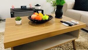 Ein Holztisch mit einer Obstschale, einem kleinen Topfpflanzen, einer Vase mit Tulpen und zwei Fernbedienungen.